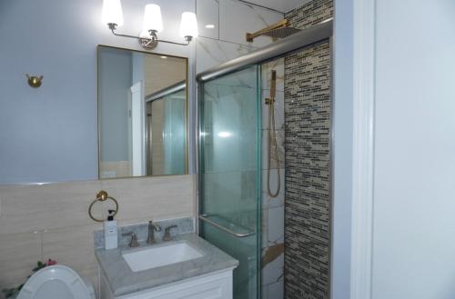 a bathroom with a sink and a glass shower at New York private room 31 in West New York