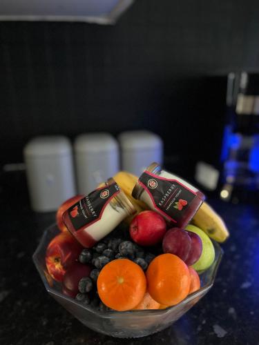 a bowl of fruit on a table with yogurt and oranges at Abbey Meadows View ABB in Redditch