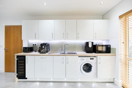 a kitchen with white cabinets and a washing machine at Haven - Spacious Luxury Home perfect for families, couples and contractors! 5mins to Xscape and Junction 32! in Castleford