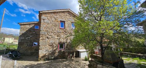 a stone house with a tree in front of it at Ares do Montemuro in Campo Benfeito