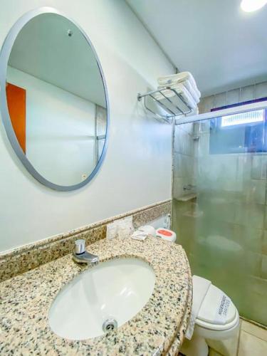 a bathroom with a sink and a mirror and a toilet at Garbos Soleil Hotel in Natal