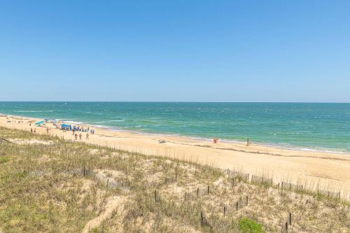 a group of people on a beach near the ocean at Ocean Song - 2 Bedroom Oceanfront Penthouse Condo in Kill Devil Hills, Spacious Layout in Kill Devil Hills