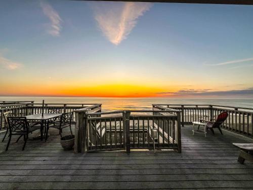 a wooden deck with tables and chairs on the beach at Ocean Song - 2 Bedroom Oceanfront Penthouse Condo in Kill Devil Hills, Spacious Layout in Kill Devil Hills