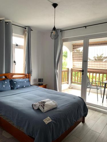 a bedroom with a blue bed with a balcony at Namastay Apartment - La Gaulette in Rivière Noire