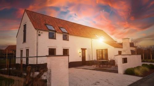 a large white house with a sunset in the background at Obobonne in Geraardsbergen