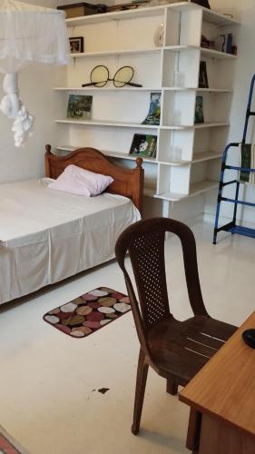 a bedroom with a chair and a bed and shelves at Oshi villa in Hikkaduwa