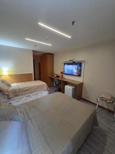 a hotel room with two beds and a flat screen tv at Flat 811 - Hotel Comfort Taguatinga in Brasília