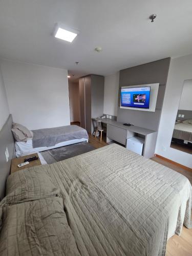 a hotel room with two beds and a flat screen tv at Flat 709 - Hotel Comfort Taguatinga in Brasília
