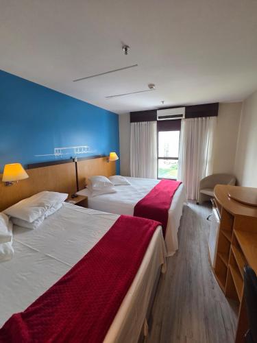 a hotel room with two beds and a desk at Flat 1015 - Hotel Comfort Taguatinga in Brasília