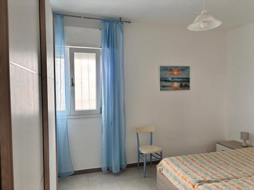 a bedroom with a bed and a window and a chair at Casa Gada in Torre Lapillo