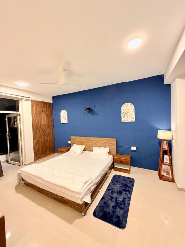 a bedroom with a large bed with a blue wall at La vida in Nalmatha