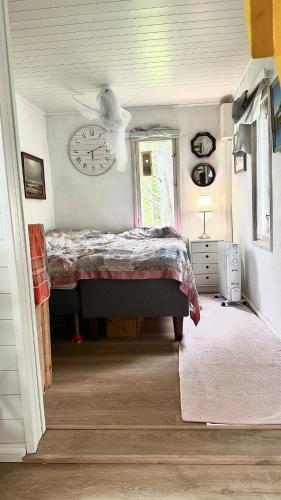 a bedroom with a bed and a clock on the wall at Summer cottage Taipalsaari in Vehkataipale