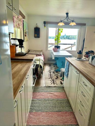a kitchen with white cabinets and a sink and a window at Summer cottage Taipalsaari in Vehkataipale