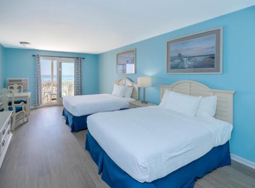 Zwei Betten in einem Hotelzimmer mit blauen Wänden in der Unterkunft Drifting Sands Oceanfront Hotel in Ship Bottom