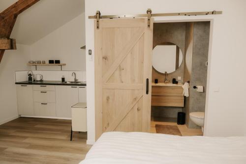 a bathroom with a sliding barn door in a bedroom at De Vlaeke in Kerkwerve