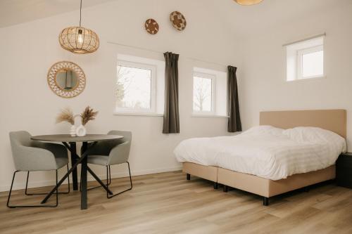 a bedroom with a bed and a table and chairs at De Vlaeke in Kerkwerve