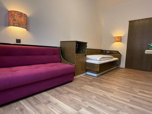 a living room with a couch and a bed at Hotel Merkur in Zwickau