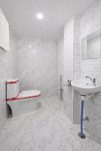 a white bathroom with a toilet and a sink at Hotel In Varanasi in Varanasi