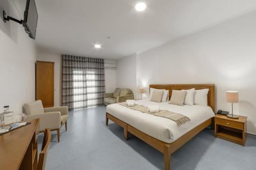 ein Schlafzimmer mit einem großen Bett und ein Wohnzimmer in der Unterkunft Hotel Pinhal Mar in Peniche