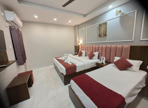 a hotel room with two beds and a tv at Hotel Shri Ji Palace in Haridwār