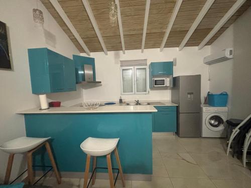 a kitchen with blue cabinets and a counter with stools at Rêve Bleu in Capesterre