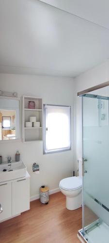 a white bathroom with a toilet and a window at Balea House in Barreiros
