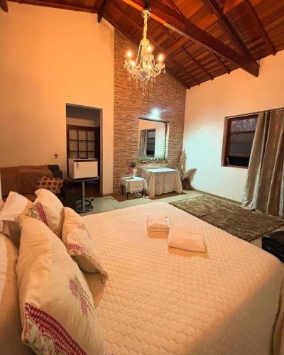 a large bed in a room with a chandelier at Pousada DrChico in Poço Fundo
