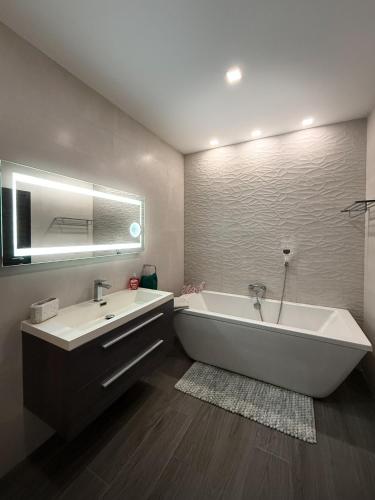 a large bathroom with a tub and a sink at Bright Modern Apartment with Rooftop in Mqabba
