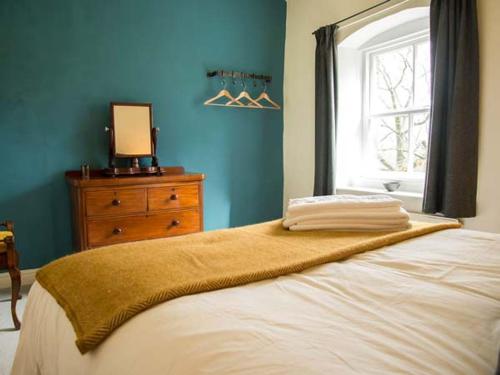 a bedroom with a bed with a window and a dresser at Beacon Cottage in Ilkley