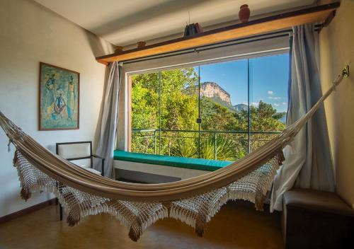 eine Hängematte in einem Zimmer mit großem Fenster in der Unterkunft Pousada do Capão Chapada Diamantina in Vale do Capao