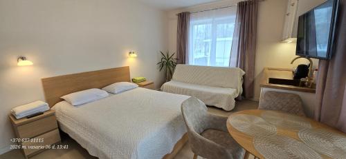 a hotel room with a bed and a table at Apartamentai šalia baseino in Palanga