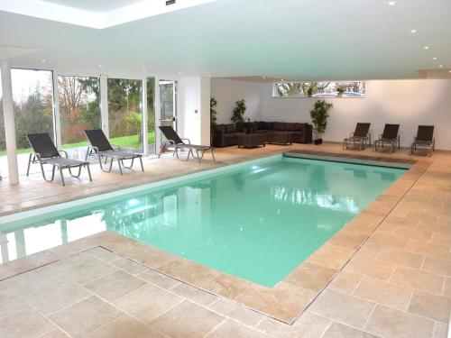 a swimming pool in a house with chairs and a couch at stunning Family Gîte Retreat in Stoumont