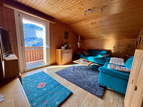a living room with a blue couch and a window at Staldenried Ferienwohnung in Staldenried