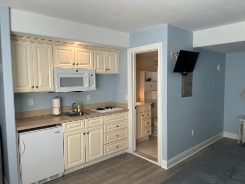 a kitchen with white cabinets and a white microwave at Sunbeach Condo 900 Wesley Avenue Unit 109 in Ocean City