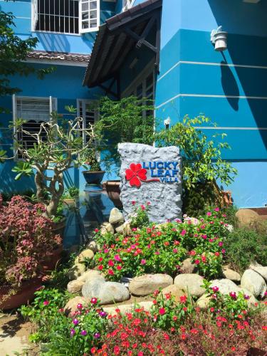 a garden in front of a blue house with flowers at Lucky Leaf Hoian Villa in Hoi An