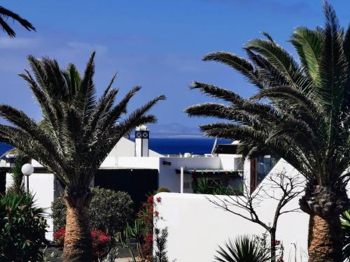 a house with palm trees in front of the ocean at Studio Paraíso - Casa Paraíso Playa Blanca in Playa Blanca