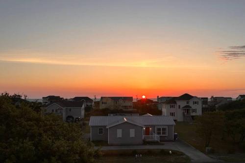 a sunset over a residential neighborhood with houses at King BEEch - Southern Shores, 300 Yds to Beach, Ocean View, Pool, Hot Hub, Fenced Yard in Southern Shores