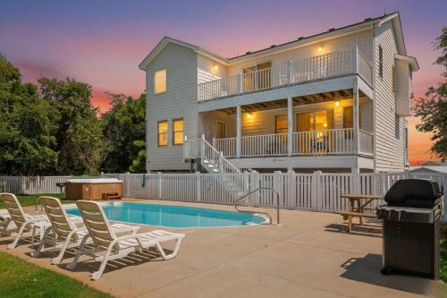 a house with a swimming pool and chairs in front of it at King BEEch - Southern Shores, 300 Yds to Beach, Ocean View, Pool, Hot Hub, Fenced Yard in Southern Shores