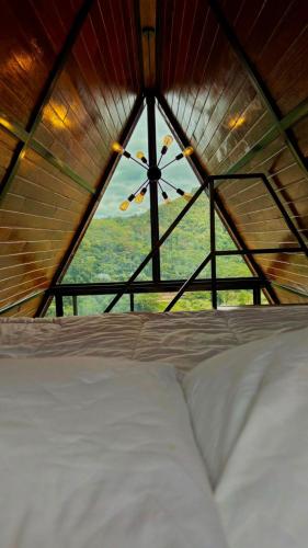 a bed in a room with a large window at Chalé Vale da Cachoeira in Três Rios