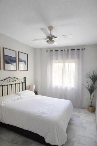 a white bedroom with a bed and a ceiling fan at La Alcazaba de Cristina in El Puerto de Santa María