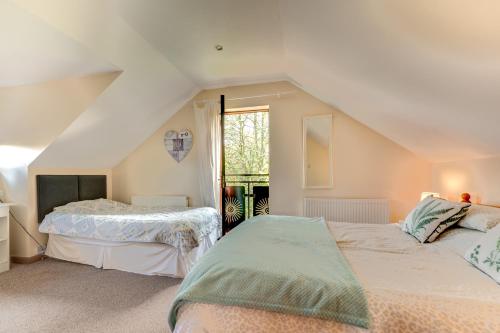 a attic bedroom with two beds and a window at The Loft at Duffryn Mawr Self Catering Cottages in Hensol