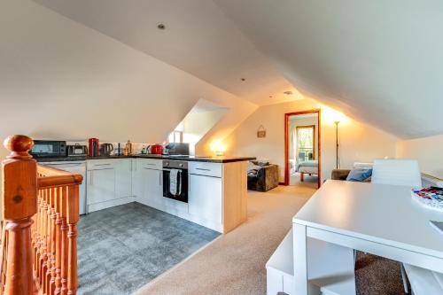 a kitchen with white cabinets and a living room at The Loft at Duffryn Mawr Self Catering Cottages in Hensol