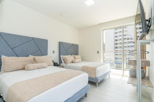 a bedroom with two beds and a large window at Hotel Marco Polo Rodadero in Santa Marta