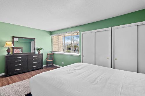 a bedroom with green walls and a bed and a mirror at Emerald Breeze in Destin