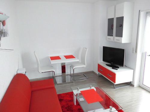 a living room with a red couch and a tv at Ferienwohnung Schwalbennest in Kronau