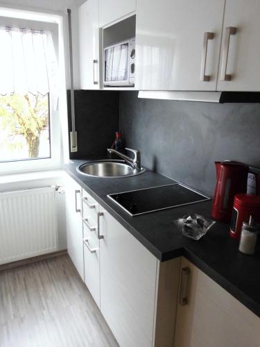 a kitchen with white cabinets and a sink and a window at Ferienwohnung Schwalbennest in Kronau