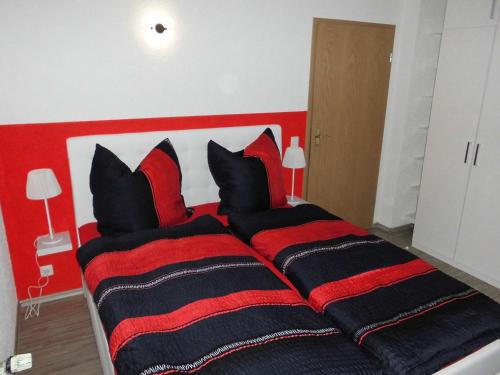 a bedroom with a large bed with red and black pillows at Ferienwohnung Schwalbennest in Kronau