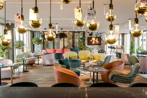 a lobby with chairs and tables and chandeliers at Motel One Rotterdam in Rotterdam