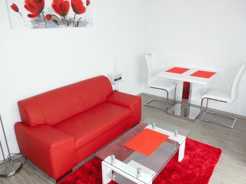 a living room with a red couch and a table at Ferienwohnung Schwalbennest in Kronau