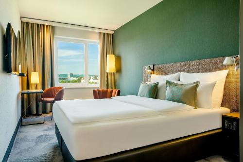 a hotel room with a large white bed and a window at Motel One Wien-Prater in Vienna